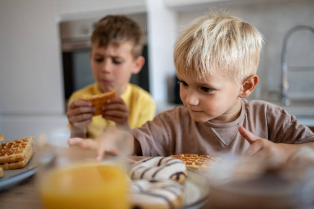 istock Two brothers having breakfast with waffles and orange juice 2204747829