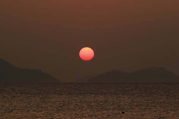 The evening sky at Kampung Jawa Beach, Banda Aceh, radiates a stunning gradient of gold and orange hues. Gentle waves wash over the sand, creating harmony between the sea and the slowly setting sun. The silhouette of fishing boats enhances the natural beauty, offering a serene and captivating view to all who witness it.