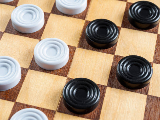 istock Checkers game setup on a checkered board. Strategy, game pieces, black and red, ready to play, board game. 2204748403
