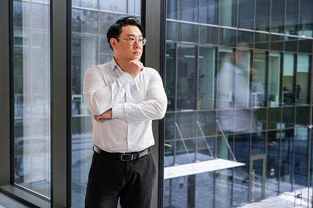 istock Professional Businessman Standing Thoughtfully by a Window in a Modern Office 2204750298