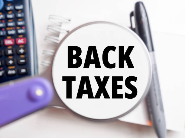 istock Back Taxes text under magnification tax background 2204750366