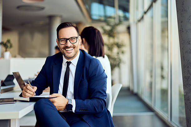 istock Confident Businessman Smiling at Desk in a Bright Modern Office Environment 2204752298