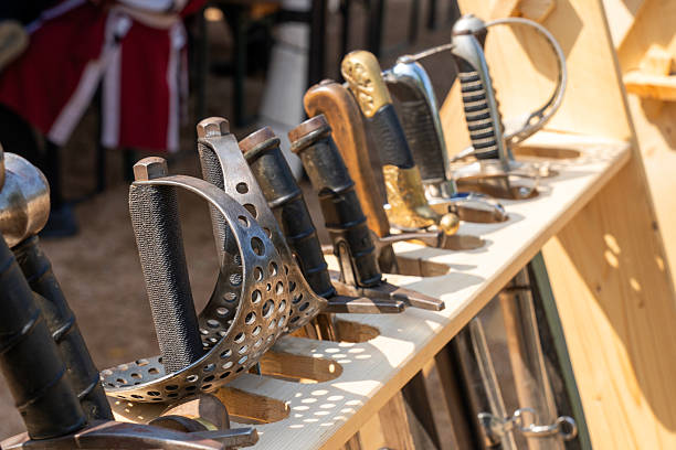 Medieval swords helmets and knight armor displayed upright on a table
