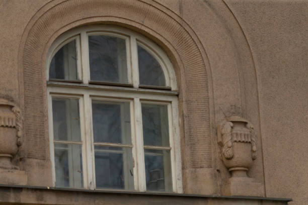There is a beautifully designed window positioned on the side of a building, featuring elegant arched windows that enhance its architectural charm