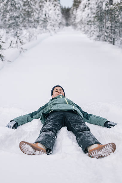 istock Teenager making snow angel in a snowy forest path 2204756608