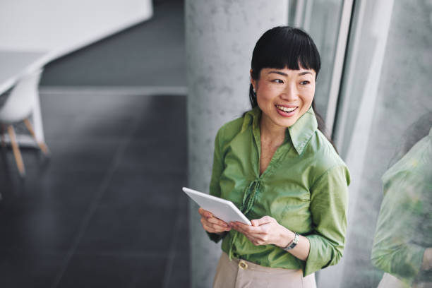 istock Japanese businesswoman smiling and using digital tablet in office 2204758415