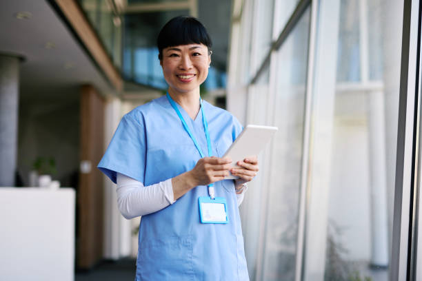 istock Japanese Nurse smiling and using digital tablet in hospital corridor 2204759041