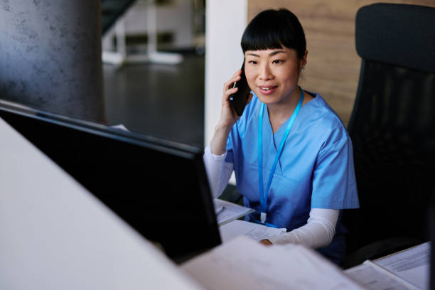 istock Japanese Nurse Talking on the Phone and Working on Computer 2204759171