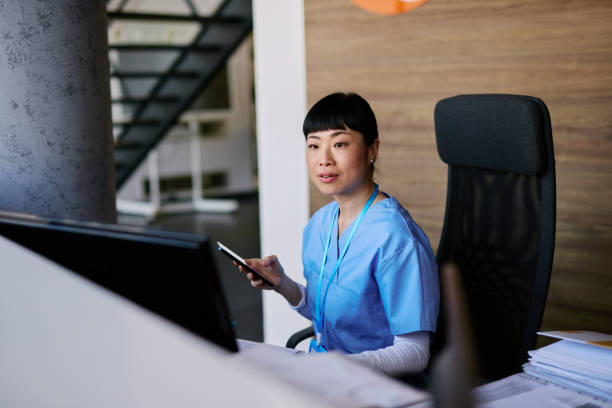 istock Japanese Nurse working at hospital reception using smartphone and computer 2204759173