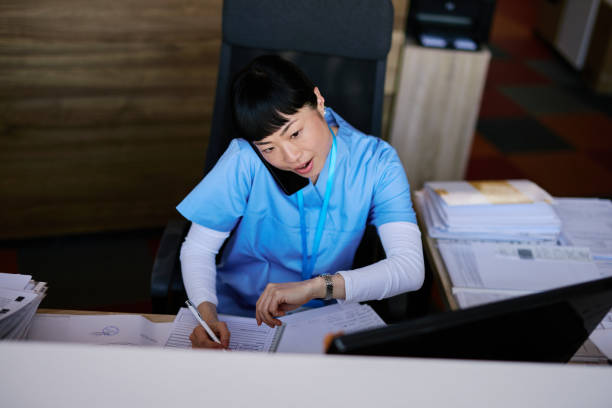 Japanese Nurse managing appointments and checking time while speaking on the phone