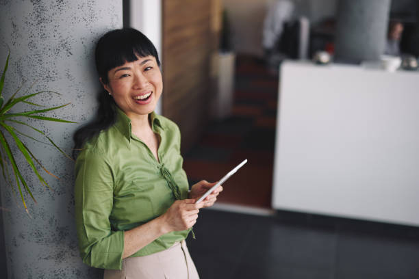 istock Smiling asian businesswoman using digital tablet in office 2204759745