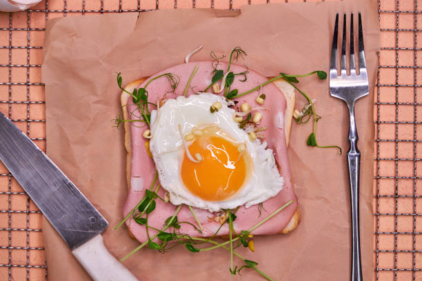istock Toast with a glazed egg rests on parchment with vegetables and herbs on a pink background 2204761966