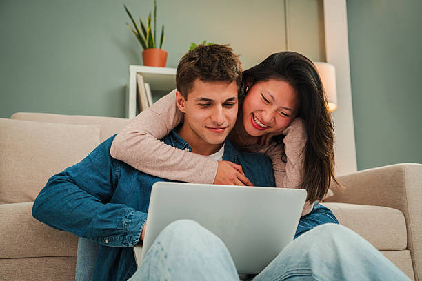 istock Joyful couple enjoying quality time together while using a laptop on the couch, sharing laughter and happiness in a cozy, intimate connection, perfect for capturing love and togetherness 2204764664