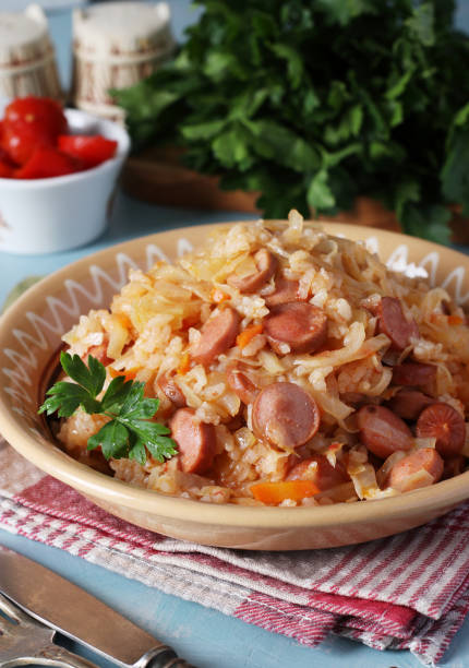istock Braised cabbage with rice and sausages in a plate on a blue background, Close up 2204765974