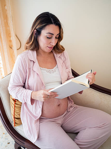 istock Expecting mother reads a book while relaxing at home 2204766366