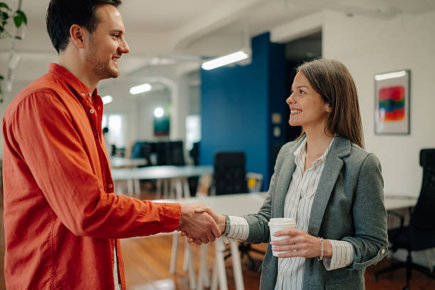 istock Two young businesspeople shaking hands in modern office 2204767580
