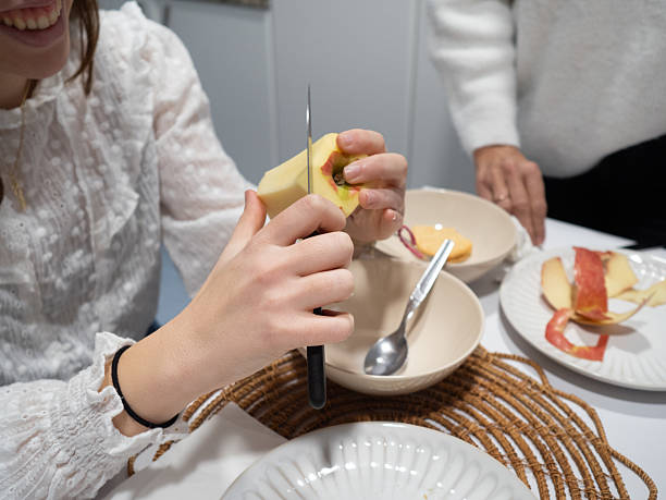 istock Young woman slices an apple at a kitchen table 2204768309
