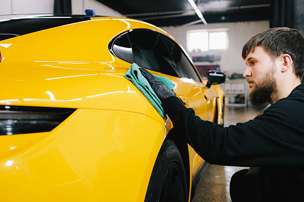 Manual washing and polishing car with microfiber cloth after detailing procedure. Microfiber hand cleaning and washing sports car using microfiber towel in garage