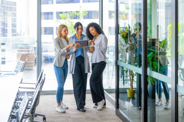 Three business women working looking at digital tablets.