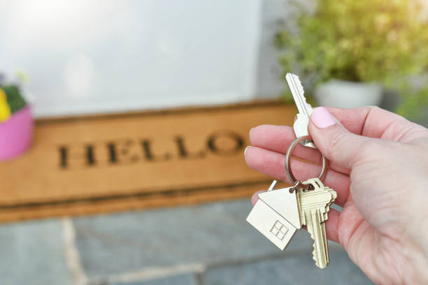New house real estate concept keys by front door welcome mat Female hand holding a set of keys over a welcome mat that says HELLO key doormat stock pictures, royalty-free photos & images