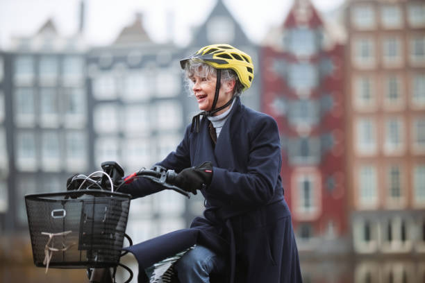 Elderly Woman Riding Bicycle in Urban Setting with Iconic Architecture