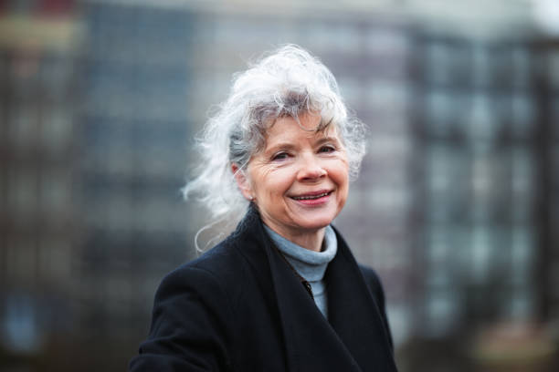 Smiling Senior Woman Outdoors in a Black Coat with a Blurred Background