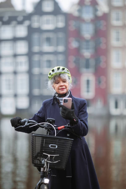 istock Mature Woman Cycling in Urban Setting Using Smartphone Near Water Reflection 2204781082