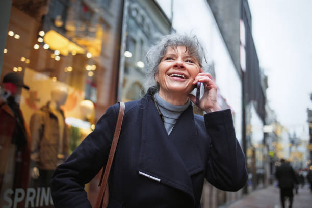istock Senior Woman Smiling While Talking on a Mobile Phone in Urban Area 2204781101
