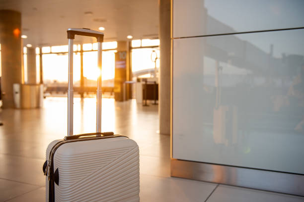 White suitcase resting in a modern airport terminal at sunset, capturing the essence of embarking on a journey and embracing the thrill of travel adventures