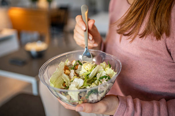 istock Woman eating fresh caesar salad at home 2204782541