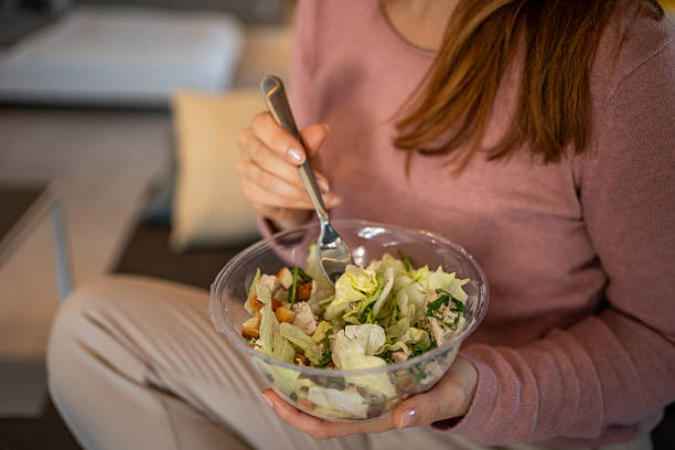 istock Young woman eating caesar salad at home 2204782553