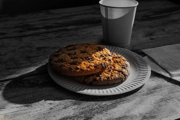 Homemade large chocolate cookie, giant chocolate cookie on a disposable plate next to a disposable cup â a hint of a quick yet delicious treat.