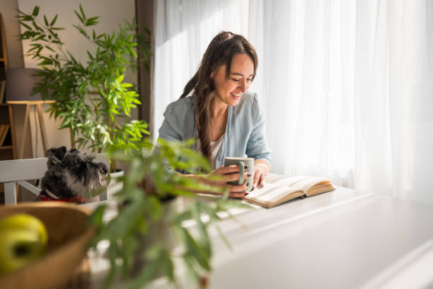 istock Young woman reading a book and drinking coffee with her dog 2204788261