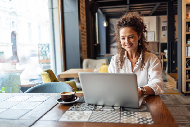 Freelancer working on laptop in coffee shop enjoying cappuccino