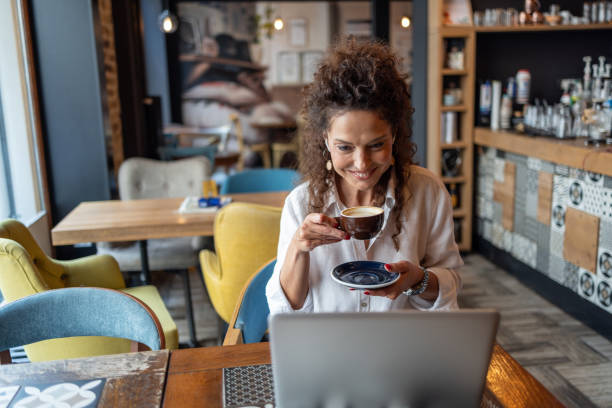 istock Businesswoman enjoying cappuccino while working on laptop in cafe 2204793295