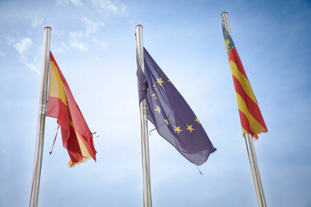 istock Three flagsSpain, the European Union, and Comunidad Valencianaflutter side by side, representing cultural unity and regional pride against a clear sky. Spain is a member of the European union. 2204795733