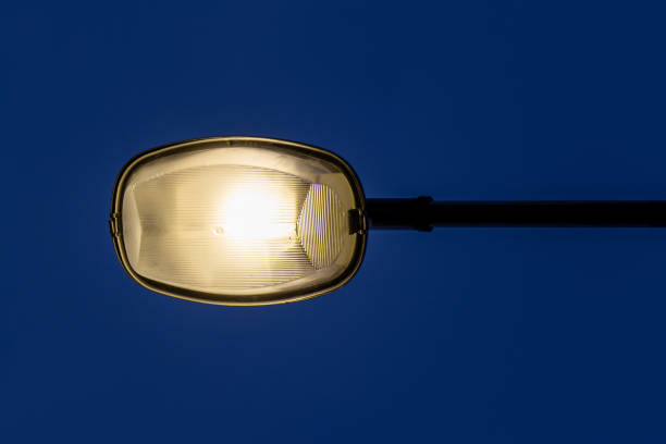 Street lamp shining against dark blue sky.