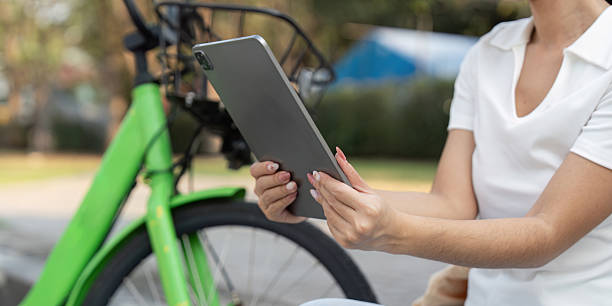 istock Exploring Sustainability and Connectivity. Woman using a tablet while paused on her green bike, symbolizing sustainable commuting and digital engagement. 2204806253