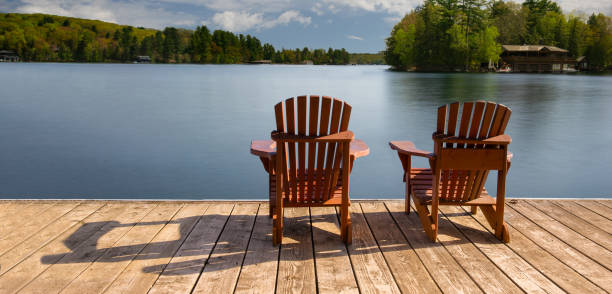 istock Two Adirondack chairs on a dock, overlooking a tranquil Muskoka lake. 2204814731