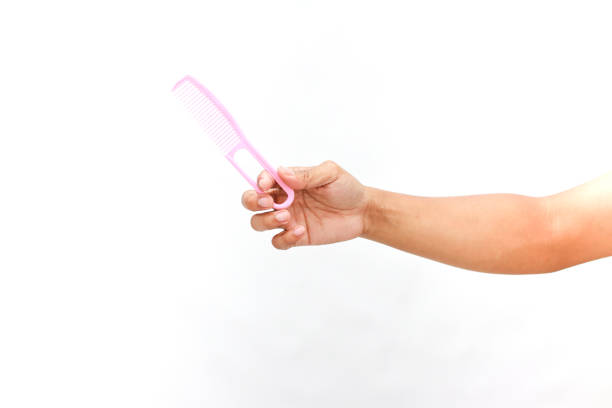 Hand holds a soft pink comb on a clean white background for personal grooming.