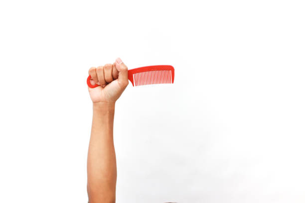 A raised hand holding a bright red comb against a stark white background.