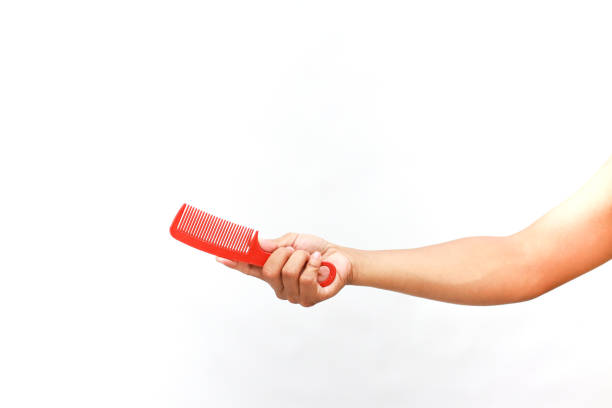 Hand holding a red comb on white. Styling tool for hair care and personal grooming