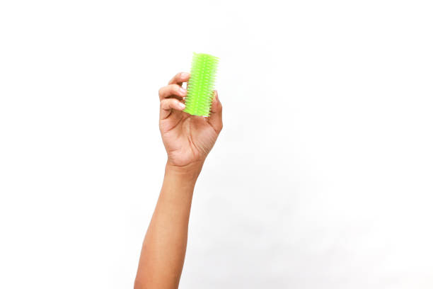 istock Hand holding vibrant green massage brush, isolated on a clean white backdrop 2204819427