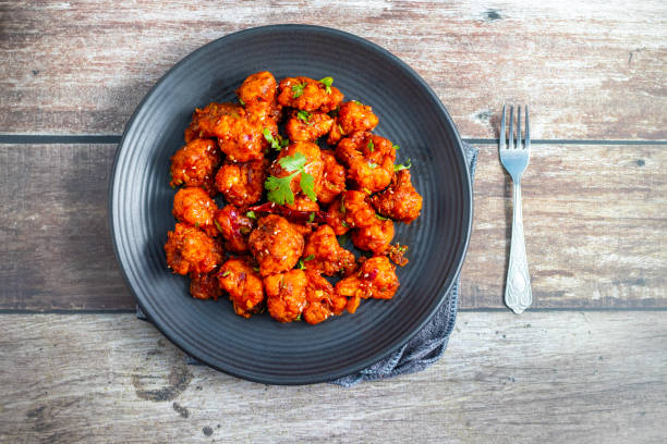 istock Gobi Manchurian is a crispy, spicy Indo-Chinese dish made with battered, fried cauliflower tossed in a tangy, flavorful soy-garlic sauce 2204824475