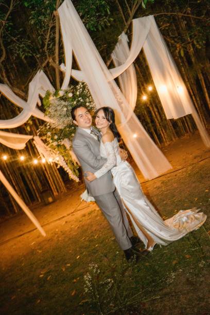 istock Newlyweds Share a Romantic Moment Under Wedding Lights Looking at Camera 2204826812