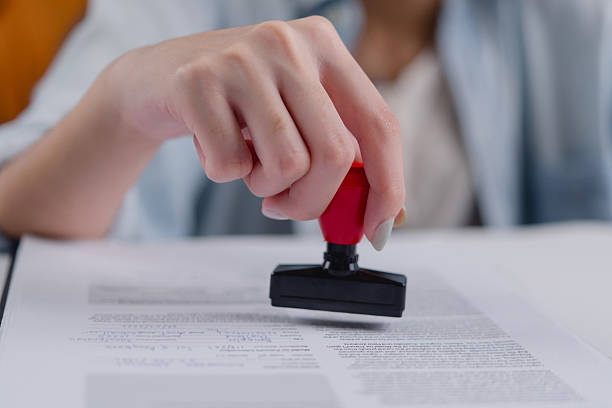 istock Businesswoman authorizing a contract with a notary rubber stamp, symbolizing certification and compliance.concept business law, finance, and administration. 2204828131