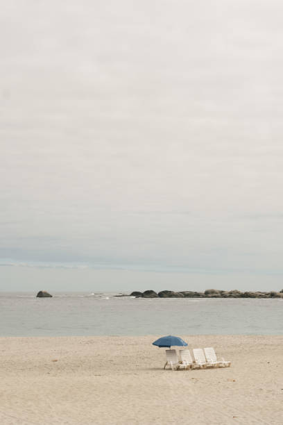 Two folding deckchairs side by side on a sunny beach, facing the ocean.