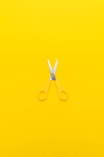 istock Flat lay vertical shot of opened yellow scissors with central composition 2204832808