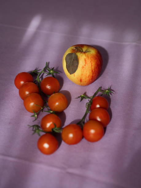 Cherry Tomatoes and an Apple on Purple Tablecloth, Vertical Top-Down Sunlit View