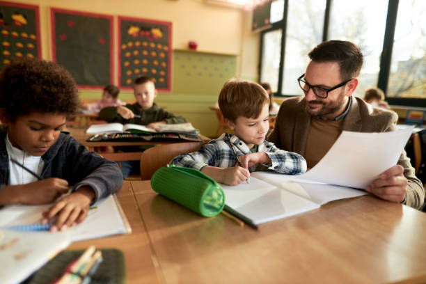 istock Smiling professor assisting schoolboy on a class at school. 2204837818